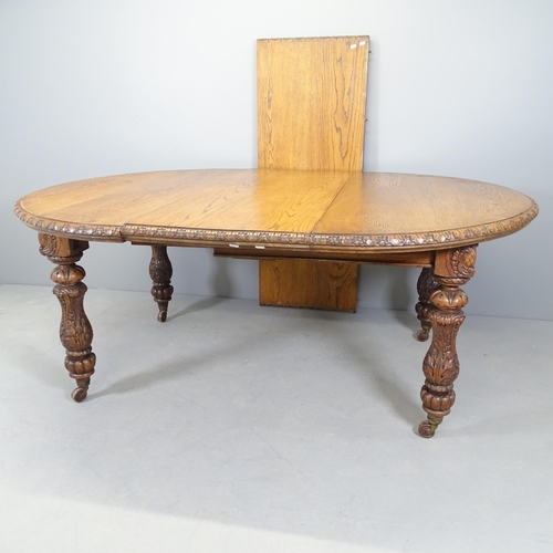 2557 - A Victorian oak wind-out dining table, with spare leaf, all over carved decoration and raised on cas... 