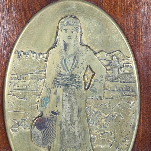 55 - J. Kazazian?, an embossed oval bronze plaque, study of a Middle Eastern water carrier, mounted on te... 