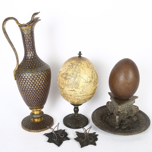 199 - A Persian brass ewer, with snake handle and knop, a Scrimshaw carved ostrich egg on stand, another, ... 