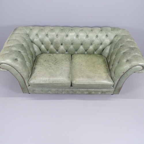 2193 - A green button back leather upholstered Chesterfield sofa with rollover arms, and raised on turned l... 