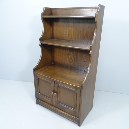 2245 - An Ercol waterfall open bookcase, with cupboards to base. 62x110x36cm.