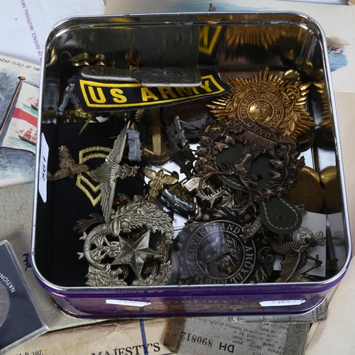 561 - A filing box containing military paperwork, and a tin with badges