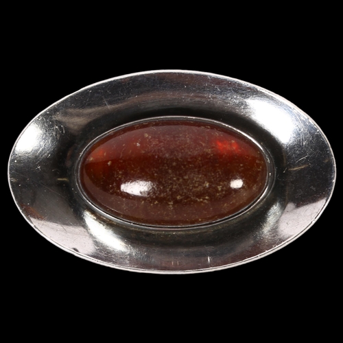 1002 - NIEL ERIK FROM - a sterling silver and oval amber set shaped brooch