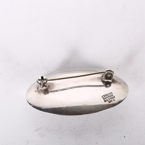 1002 - NIEL ERIK FROM - a sterling silver and oval amber set shaped brooch