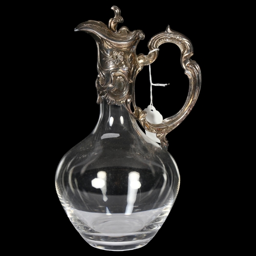 904 - A glass Claret jug with scrolled and embossed silver plated mount and handle, H28cm