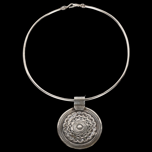 967 - An Egyptian silver pendant neck torque, stylised design, internal diameter 40cm, pendant diameter 62... 