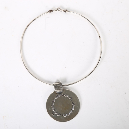 967 - An Egyptian silver pendant neck torque, stylised design, internal diameter 40cm, pendant diameter 62... 