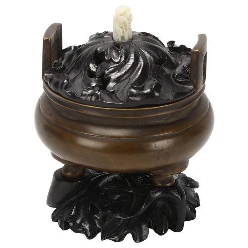 194 - A Chinese patinated bronze censer, of circular form with loop handles, the carved and pierced wooden... 