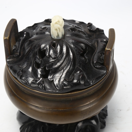 194 - A Chinese patinated bronze censer, of circular form with loop handles, the carved and pierced wooden... 