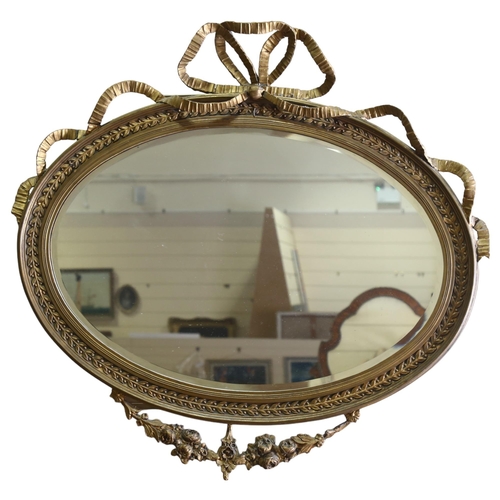 71 - An oval gilt-gesso framed wall mirror, with ribbon pediment, circa 1920, width excluding ribbons 87c... 