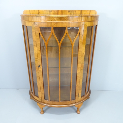 2005 - A 1930s walnut bow-front display cabinet, with three fitted glass shelves and raised on cabriole leg... 