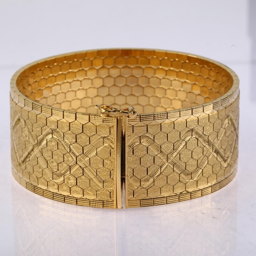 1137 - A heavy Swiss 18ct gold cuff bracelet, polished and textured hexagonal links with engraved lozenge d... 