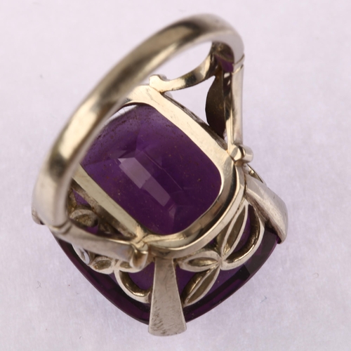 1143 - A large late 20th century amethyst dress ring, unmarked white metal settings, set with oval mixed-cu... 