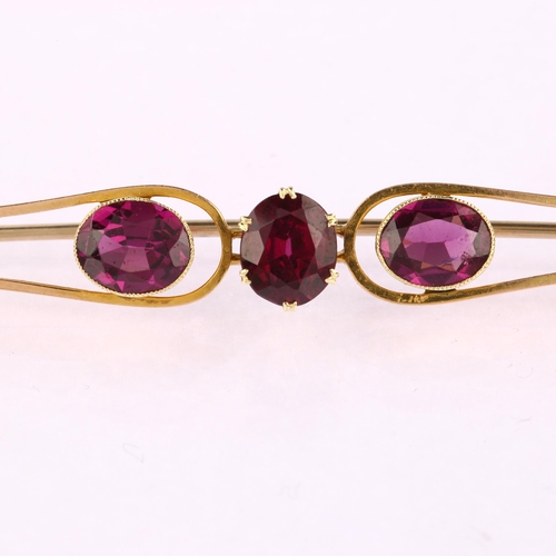 1186 - A large early 20th century three stone amethyst openwork bar brooch, unmarked gold settings with ova... 