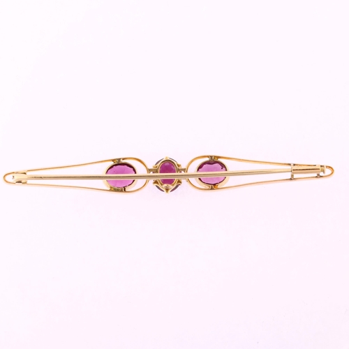 1186 - A large early 20th century three stone amethyst openwork bar brooch, unmarked gold settings with ova... 