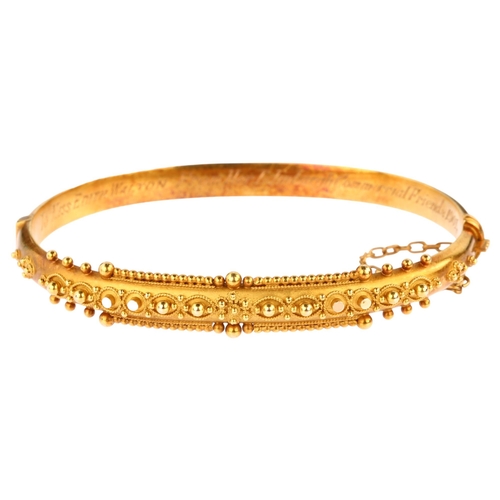 1215 - A 15ct gold Etruscan Revival hinged bangle, with wirework decoration and personalised inscription da... 