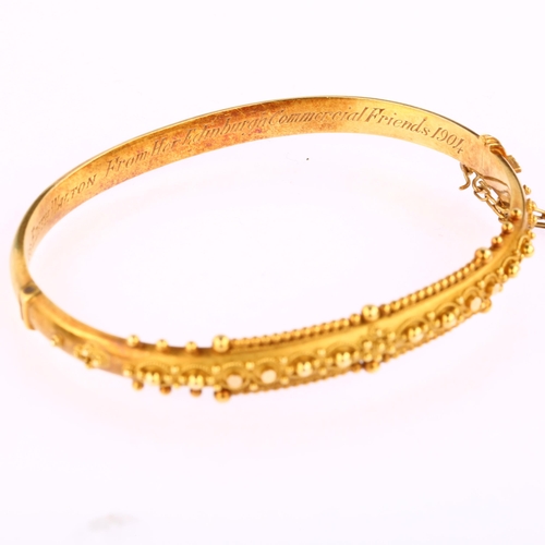 1215 - A 15ct gold Etruscan Revival hinged bangle, with wirework decoration and personalised inscription da... 