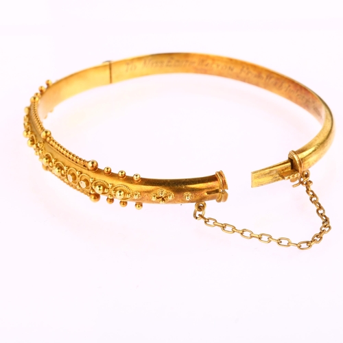 1215 - A 15ct gold Etruscan Revival hinged bangle, with wirework decoration and personalised inscription da... 