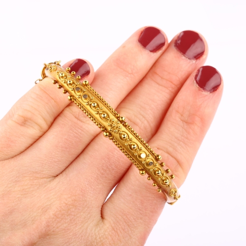 1215 - A 15ct gold Etruscan Revival hinged bangle, with wirework decoration and personalised inscription da... 