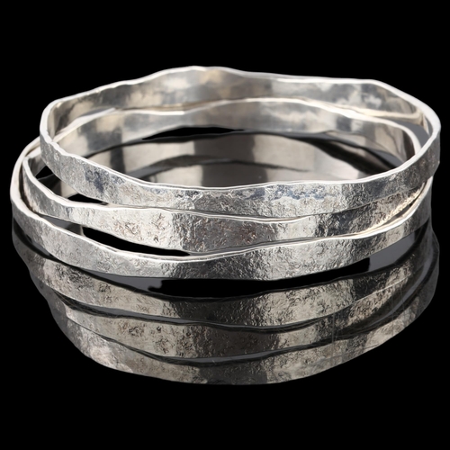 1387 - CARL JOHAN ANTONSEN - a set of 3 Danish sterling silver plain form slave bangles, textured decoratio... 