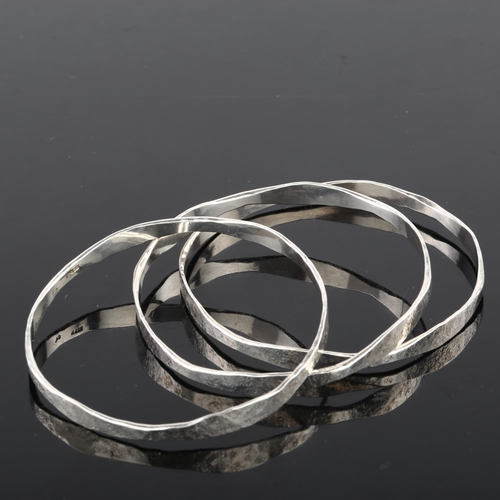 1387 - CARL JOHAN ANTONSEN - a set of 3 Danish sterling silver plain form slave bangles, textured decoratio... 