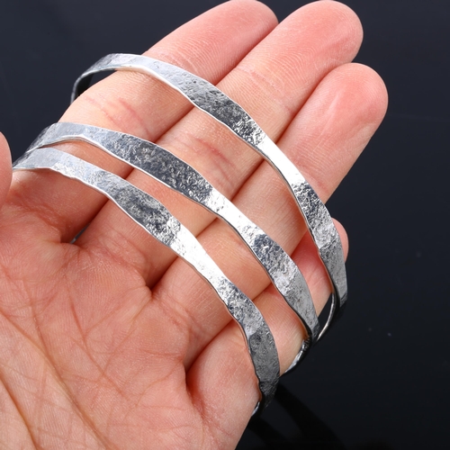 1387 - CARL JOHAN ANTONSEN - a set of 3 Danish sterling silver plain form slave bangles, textured decoratio... 