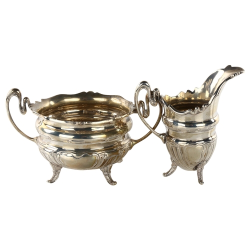 1489 - An early 20th century silver matching 2-handled sugar bowl and cream jug, waisted form with relief e... 