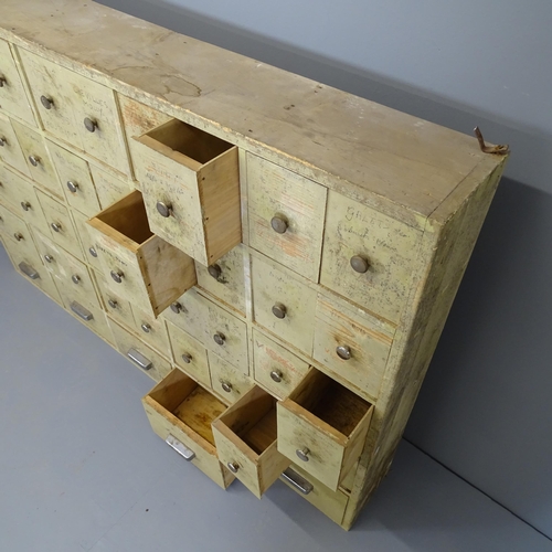 2500 - A vintage painted pine bank of 45 drawers. 161x110x24cm.