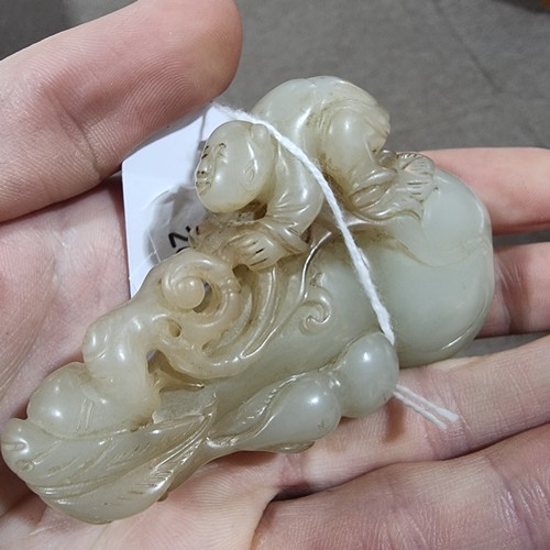 196 - A Chinese carved jade ornament depicting a man climbing a double-gourd, length 8cm