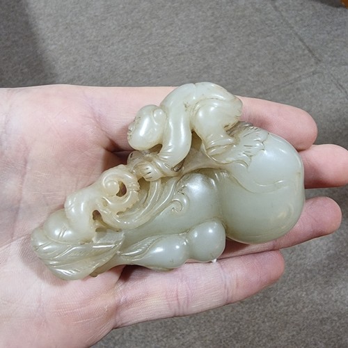 196 - A Chinese carved jade ornament depicting a man climbing a double-gourd, length 8cm