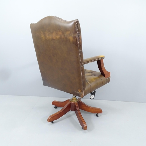 2165 - An early 20th century mahogany and button-back leather upholstered swivel lounge chair, with rise an... 