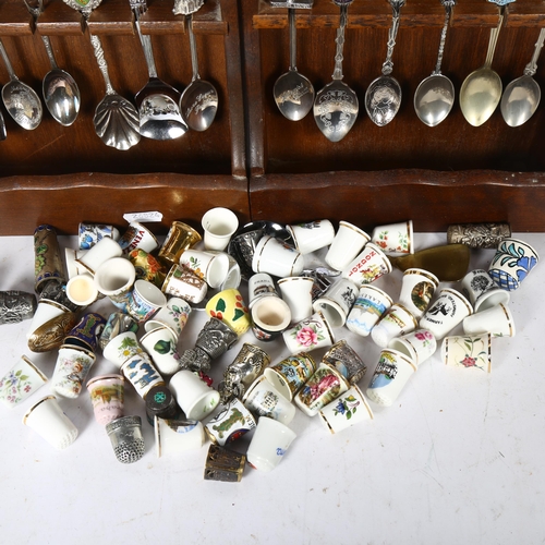 631 - A collection of porcelain and other thimbles, and 2 spoon racks with a collection of souvenir teaspo... 