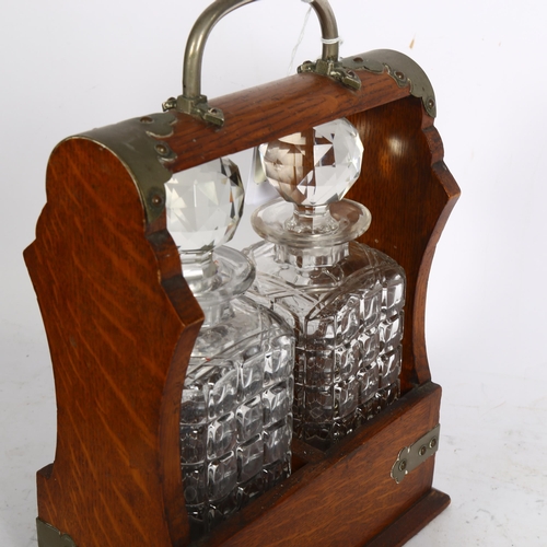 914 - An oak 2-bottle tantalus, with square section decanters, no key, W23cm, D13cm, H31cm