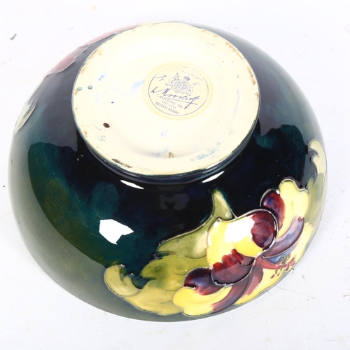 1011 - A Moorcroft green ground bowl on foot, with tube-lined Hibiscus design, with paper label, 15.5cm