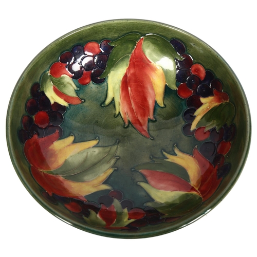 1013 - A Moorcroft green ground dish on foot, with fruit decoration, signed, 20cm diameter