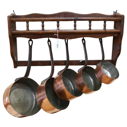 1063 - A graduated set of 5 French hammered copper and steel-handled pans, with hanging rack, width 58cm