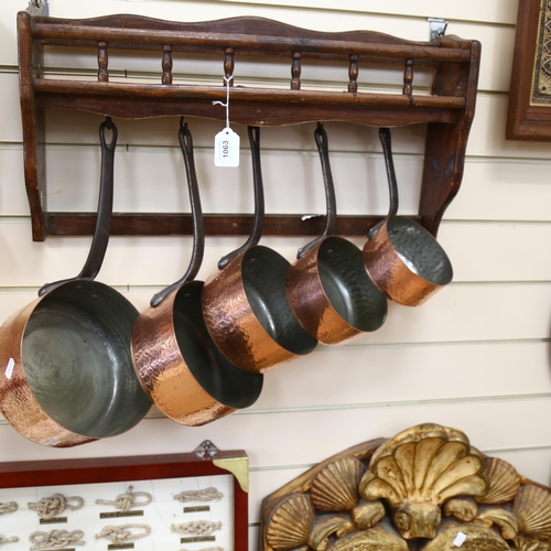 1063 - A graduated set of 5 French hammered copper and steel-handled pans, with hanging rack, width 58cm