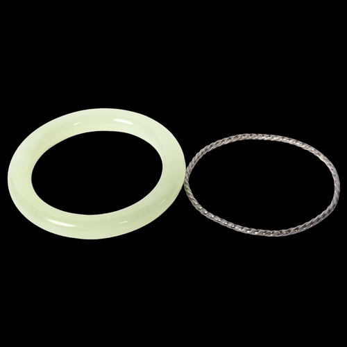 1216 - A green jadeite bangle, diameter 78mm, inside diameter 55mm, and a spiral bangle (2)