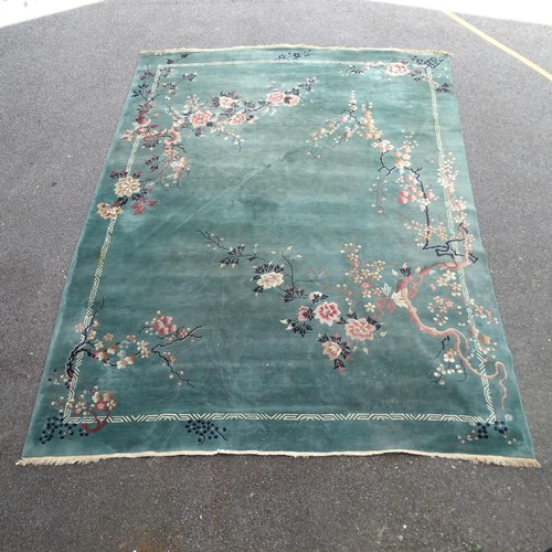 2348 - A green ground Oriental style carpet, with blossom and floral decoration. 475x365cm.