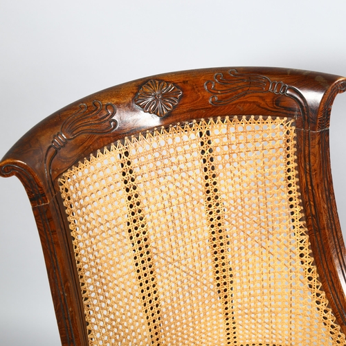 106 - An early 19th century simulated rosewood bergere tub chair in the manner of Gillows, carved show-woo... 