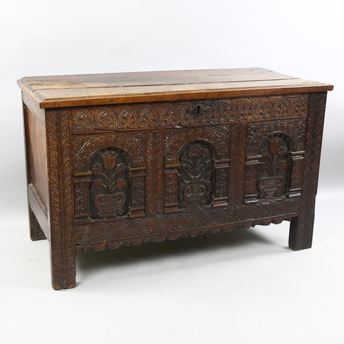 41 - A Charles I oak coffer, with plank lid, the front with 3 panels each carved with a vase of flowers w... 