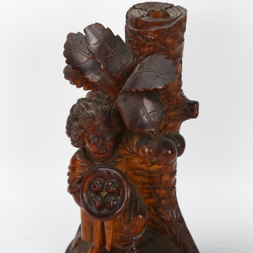 59 - A German Black Forest carved figural candlestick, depicting boy picking fruit from a tree, height 18... 