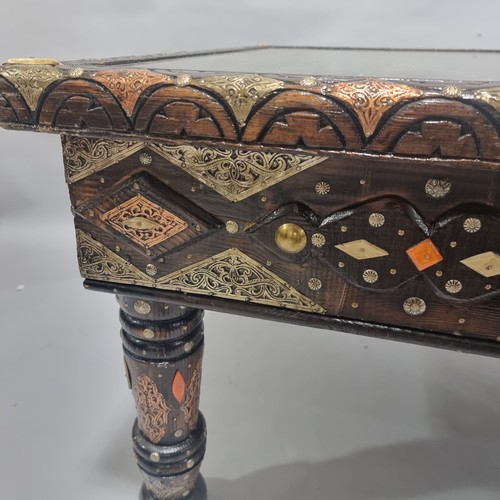 263 - An ornate Moroccan centre table, made from an Antique studded and metal inlaid door behind a glass p... 