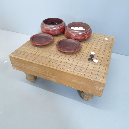 2079 - A Japanese Go set comprising two pots of counters and wooden board. 46x21x42cm.