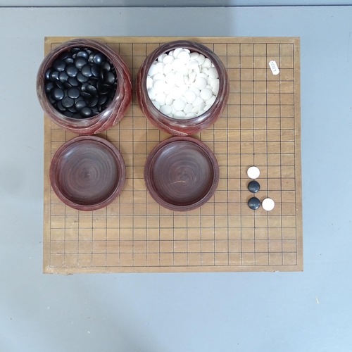 2079 - A Japanese Go set comprising two pots of counters and wooden board. 46x21x42cm.