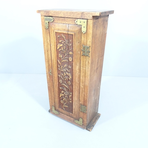 2197 - An Arts and crafts oak single door cabinet with brass mounts and applied carved foliate decoration. ... 