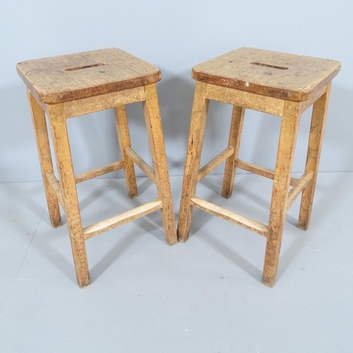 2210 - A pair of vintage oak school lab stools. 34x59x35cm.