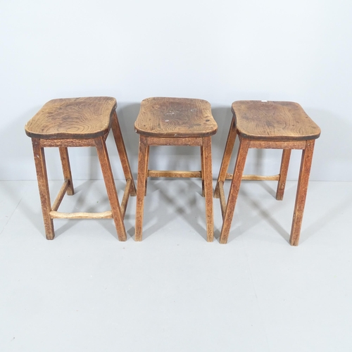 2213 - A matched set of three vintage elm-seated school lab stools. 38x60x40cm.