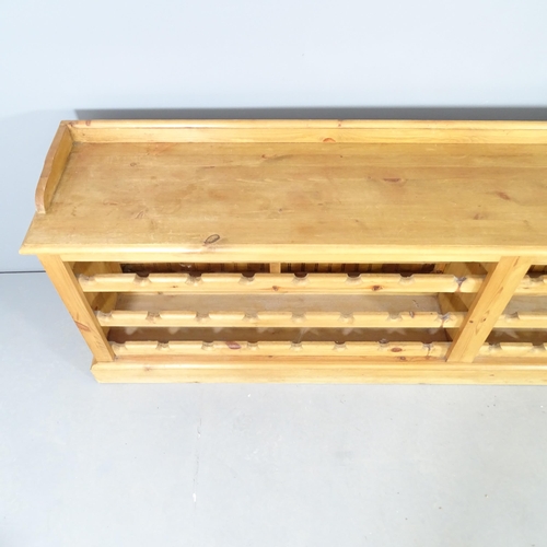 2551 - A pine 48 bottle wine rack / bench. 218x70x39cm.