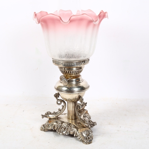 291 - An ornate oil lamp, with an etched clear and cranberry glass frilled shade, sitting on a silver plat... 